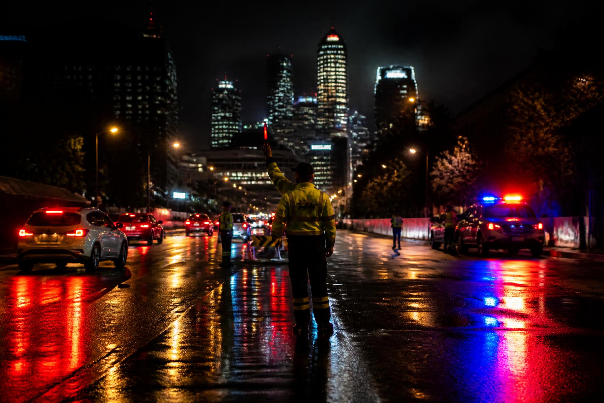CATO Group traffic controller directing traffic on a wet Sydney CBD street at night
